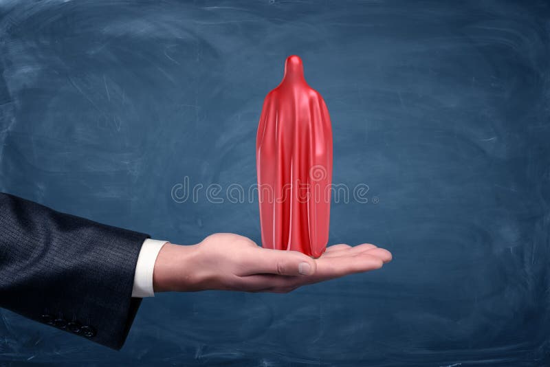 Męska palma trzyma ludzką sylwetkę zakrywająca w czerwonym płótnie na błękitnym chalkboard tle zdjęcie stock Męska palma trzyma ludzką sylwetkę zakrywająca w czerwonym płótnie na błękitnym chalkboard tle zdjęcie stock