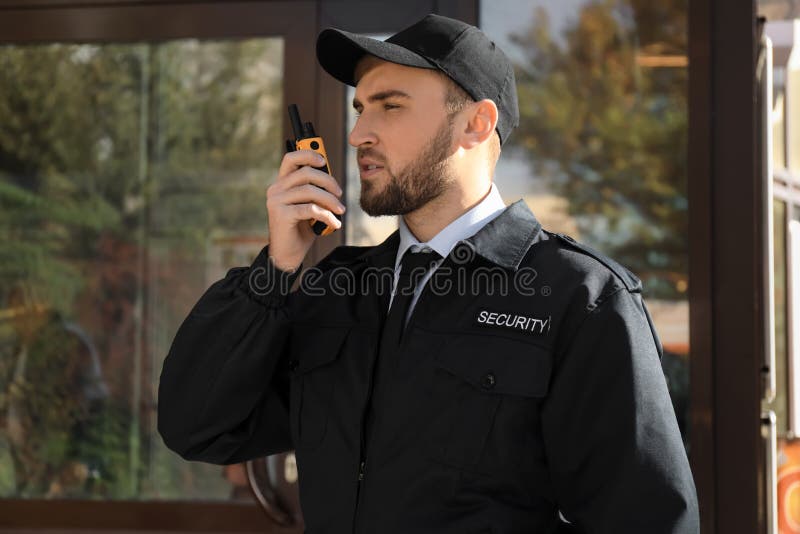 Male security guard with portable radio transmitter outdoors. Male security guard with portable radio transmitter outdoors