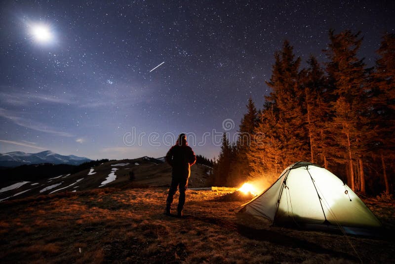 Męski turysta odpoczynek w jego obozie blisko lasu przy nocą pod pięknym nocnym niebem gwiazdy i księżyc pełno fotografia stock Męski turysta odpoczynek w jego obozie blisko lasu przy nocą pod pięknym nocnym niebem gwiazdy i księżyc pełno fotografia stock