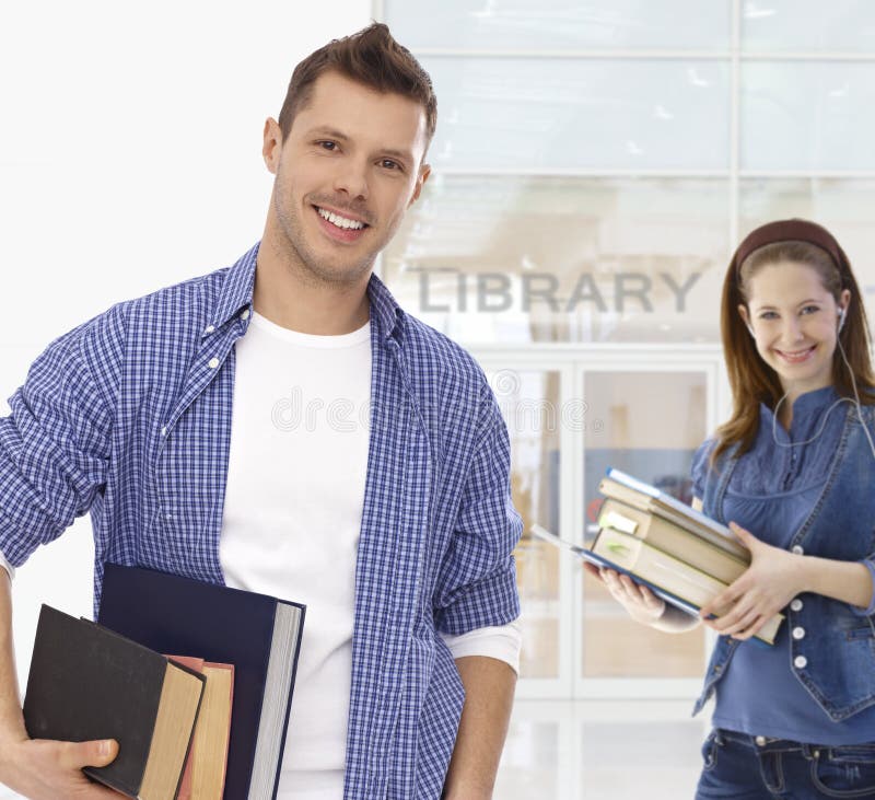 Męskiego ucznia mienia książki przy biblioteką obraz stock