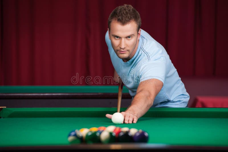 Confident young man playing pool and looking concentrated. Confident young man playing pool and looking concentrated