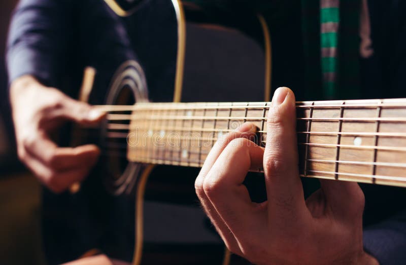 Mężczyzna bawić się muzykę przy czarną drewnianą gitarą akustyczną