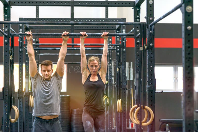 Mężczyzna i kobieta pracujący na przecinających barach w gym out obraz stock