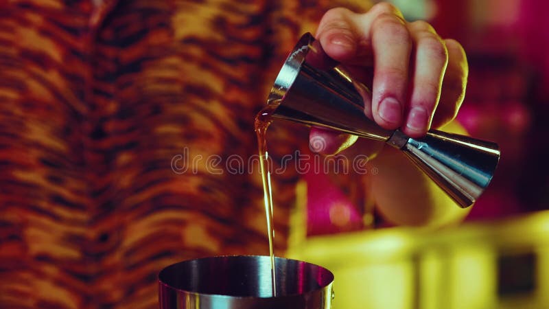 Mężczyzna m barman pracujący przy produkcji koktajlu wlewającego alkohol z jiggera do shakera. neonowy kolorowy pasek