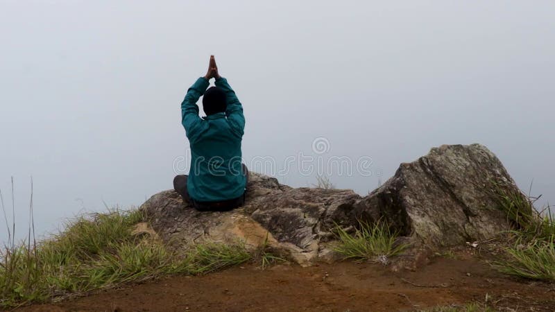 Mężczyzna medytujący w skale górskiej z białym tłem mgły z płaskiego kąta