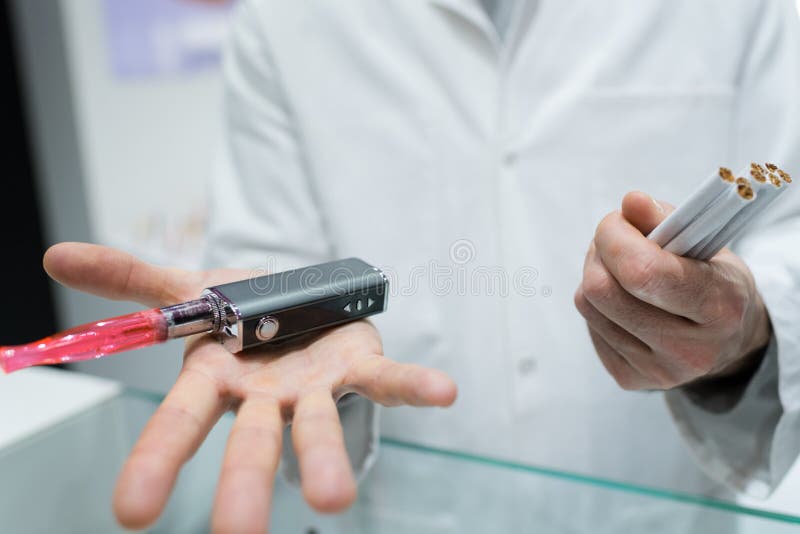 Mężczyzna mienia odparowalnik i konwencjonalni tabaczni papierosy zdjęcia stock Mężczyzna mienia odparowalnik i konwencjonalni tabaczni papierosy zdjęcia stock