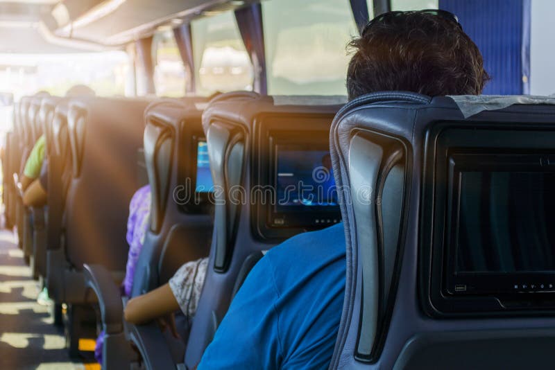 Mężczyzna na miejscu pasażera autobus słucha muzyka i spojrzenia przy pastylką Patrzeje przyrządu ` s ekran i ono uśmiecha się obrazy royalty free Mężczyzna na miejscu pasażera autobus słucha muzyka i spojrzenia przy pastylką Patrzeje przyrządu ` s ekran i ono uśmiecha się obrazy royalty free