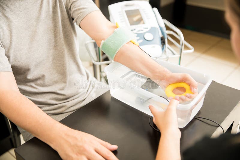 Midsection of mature man receiving electrotherapy from physiotherapist in hospital. Midsection of mature man receiving electrotherapy from physiotherapist in hospital