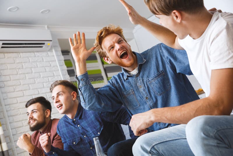Mężczyzna ogląda sport na tv daje pięć szczęśliwemu wpólnie w domu zdjęcie stock Mężczyzna ogląda sport na tv daje pięć szczęśliwemu wpólnie w domu zdjęcie stock