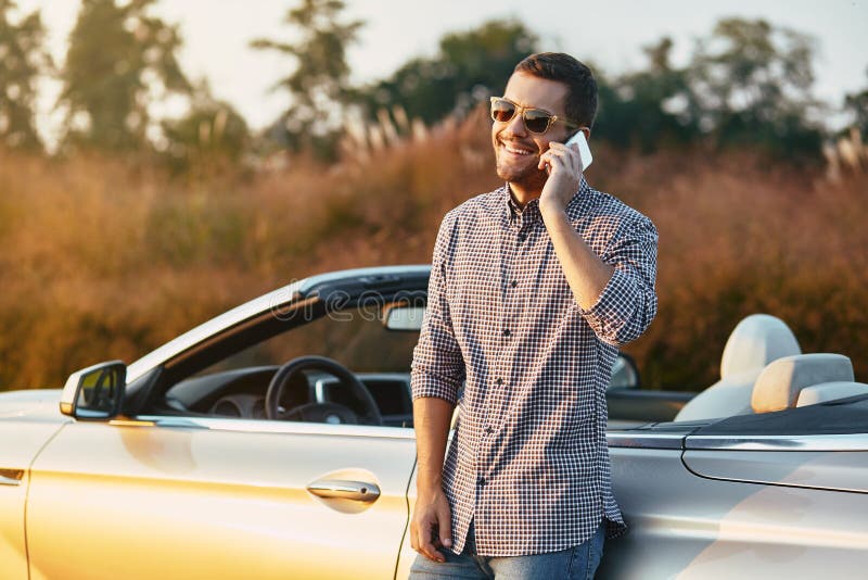 Mężczyzna opowiada na smartphone opiera cabrio fotografia stock Mężczyzna opowiada na smartphone opiera cabrio fotografia stock