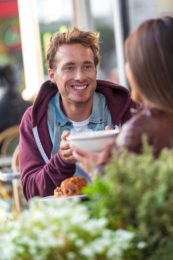 Mężczyzna opowiada z dziewczyną przy kawiarnia stołem Przyjaciele spotyka w mieście ma zabawę pije kawę Para na dacie, młodzi lud