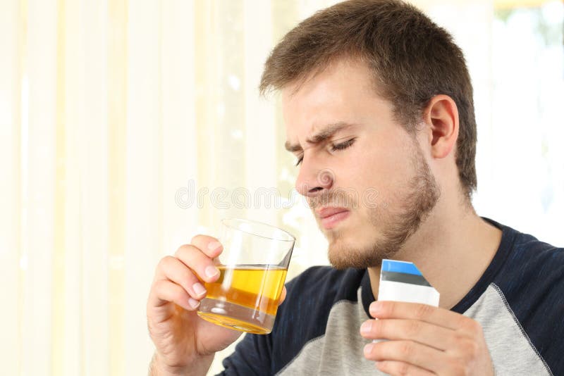 Disgusted man drinking a medicine with bad taste at home. Disgusted man drinking a medicine with bad taste at home