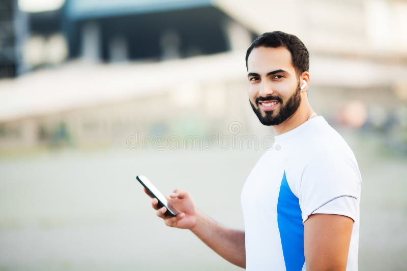 Mężczyzna po opracowywać w miasto parku i używać jego telefon komórkowego obraz stock Mężczyzna po opracowywać w miasto parku i używać jego telefon komórkowego obraz stock