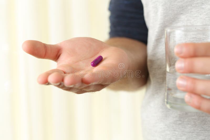 Close up of a man hand palm holding a capsule and a glass of water. Close up of a man hand palm holding a capsule and a glass of water