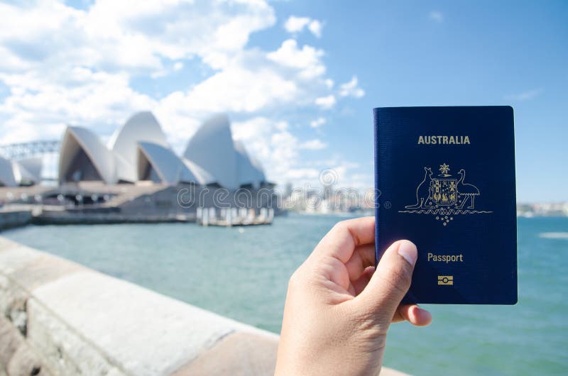 Mężczyzna ` s ręka trzyma Australia paszportowy z zamazanym tłem Sydney opera dla pojęć podróżować