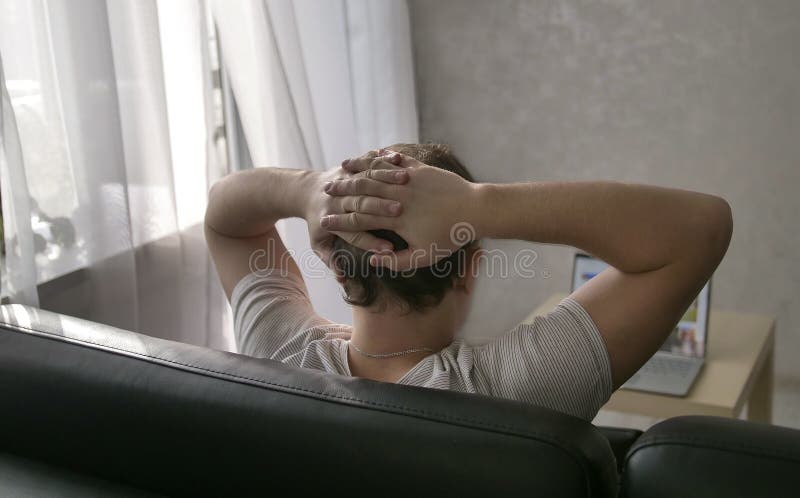 Mężczyzna siedzi w domu na spojrzeniach przy laptopu ekranem i leżance fotografia stock Mężczyzna siedzi w domu na spojrzeniach przy laptopu ekranem i leżance fotografia stock