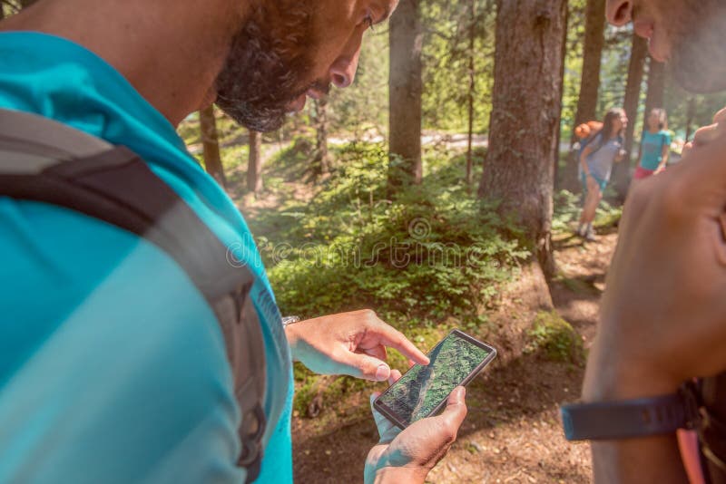 Mężczyzna sprawdza smartphone gps mapę przy wycieczkować ślad ścieżkę w lesie w fotografia royalty free Mężczyzna sprawdza smartphone gps mapę przy wycieczkować ślad ścieżkę w lesie w fotografia royalty free