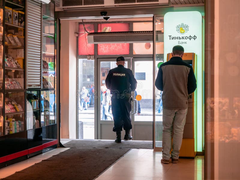 Mężczyzna stojący w pobliżu żółtego terminalu z logo Tinkoff Bank Uzbrojeni policjanci wychodzą z centrum handlowego Mężczyźni w zdjęcia royalty free