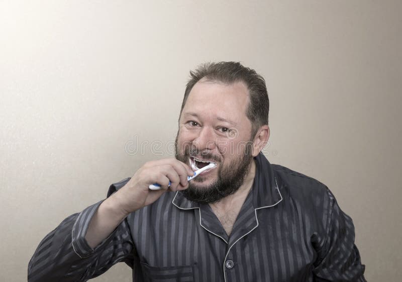 Mężczyzna szczotkuje jego zęby z toothbrush w piżamach zdjęcia royalty free Mężczyzna szczotkuje jego zęby z toothbrush w piżamach zdjęcia royalty free