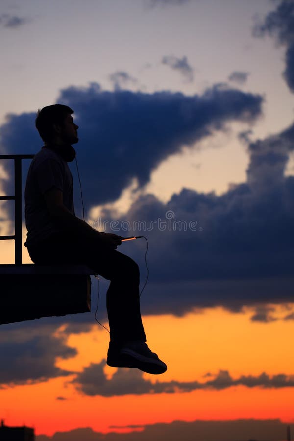 Mężczyzna słucha muzyka na dachu cloud słońca fotografia stock Mężczyzna słucha muzyka na dachu cloud słońca fotografia stock