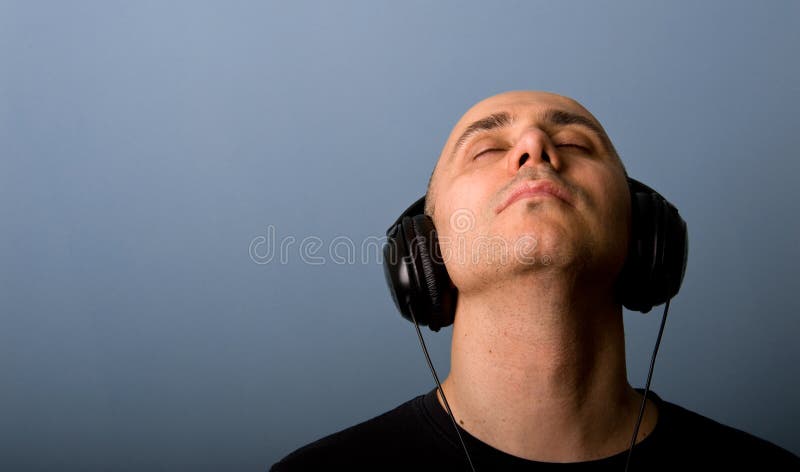 Intimate portrait of Man with ear-phones with blue background. Intimate portrait of Man with ear-phones with blue background.