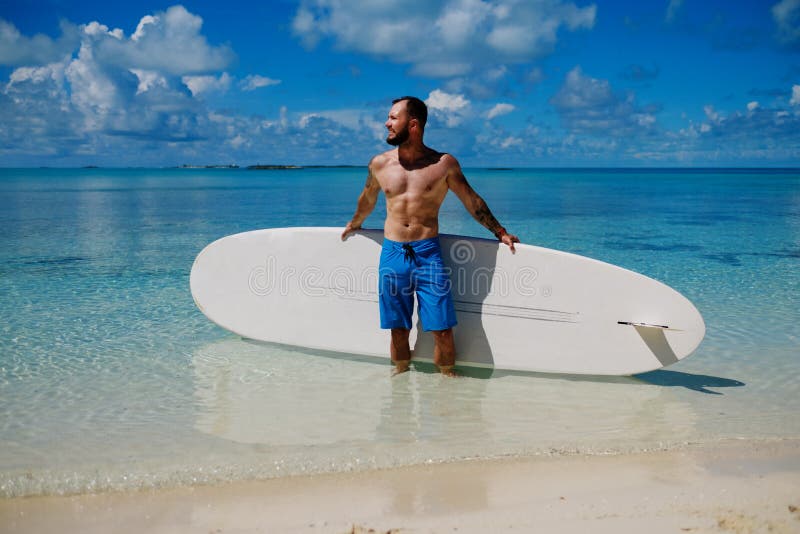 Mężczyzna z Stoi Up Paddle deskę na plaży w Bahamas obraz stock Mężczyzna z Stoi Up Paddle deskę na plaży w Bahamas obraz stock