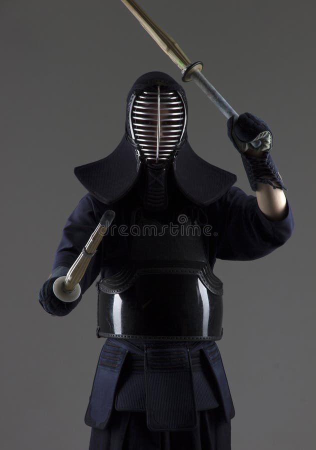 Mężczyzna ćwiczy kendo w tradycyjnym opancerzeniu On huśta się z dwa bambusowymi kordzikami fotografia stock Mężczyzna ćwiczy kendo w tradycyjnym opancerzeniu On huśta się z dwa bambusowymi kordzikami fotografia stock