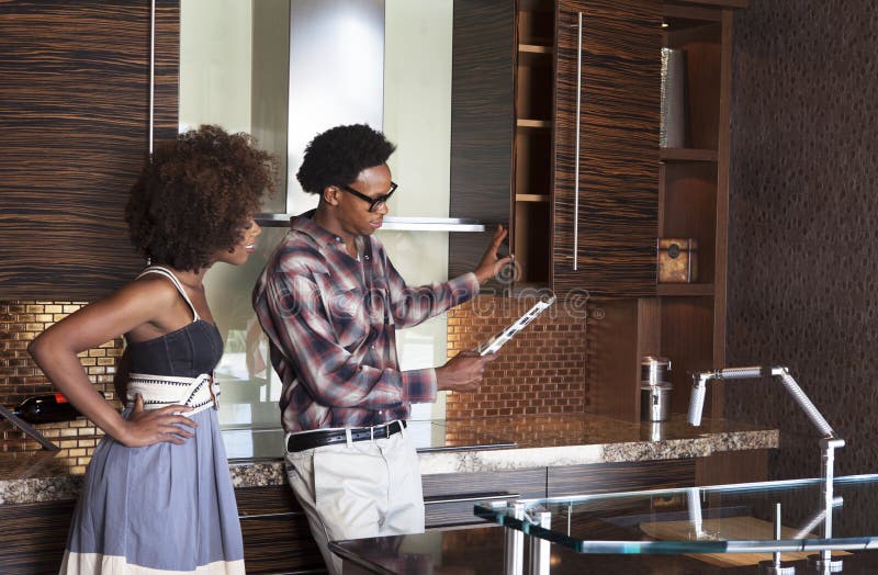 Young African American couple in new furnished Kitchen choosing materials. Young African American couple in new furnished Kitchen choosing materials