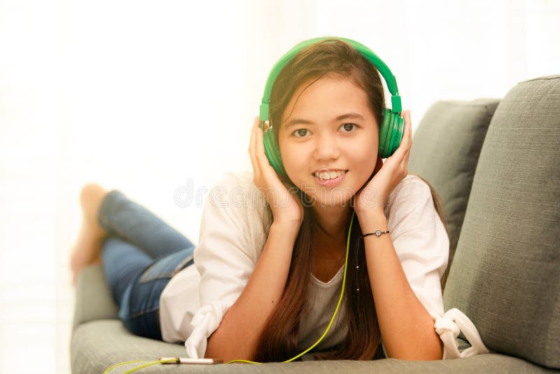 Młoda Azjatycka dziewczyna słucha muzyka z hełmofonem i smarthpho obraz royalty free Młoda Azjatycka dziewczyna słucha muzyka z hełmofonem i smarthpho obraz royalty free