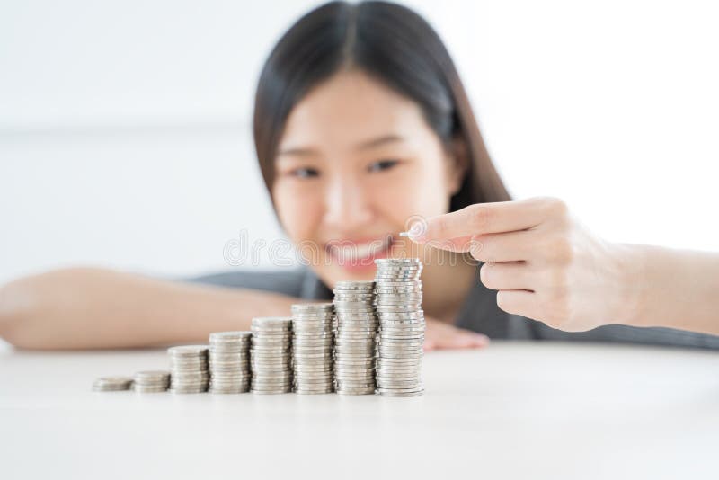 Młoda Azjatycka kobieta robi stercie monety inwestuje oprócz finansowego pojęcia