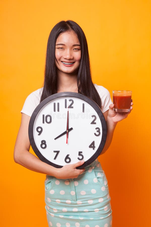 Młoda Azjatycka kobieta z pomidorowym sokiem i zegarem