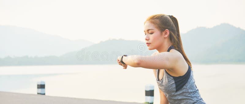 Młoda azjatykcia kobieta patrzeje sporty zegarki i sprawdza jej występ Na drodze fotografia royalty free Młoda azjatykcia kobieta patrzeje sporty zegarki i sprawdza jej występ Na drodze fotografia royalty free