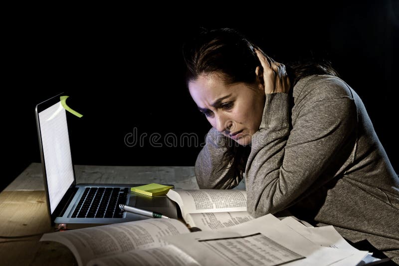 Młoda desperacka student uniwersytetu dziewczyna w stresie dla egzaminu studiowania z książkami póżno i komputerowym laptopem prz