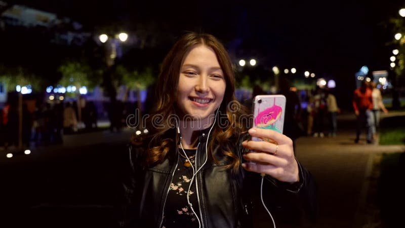 Młoda dziewczyna korzystająca z telefonu komórkowego na ulicy wieczorem Wolny ruch