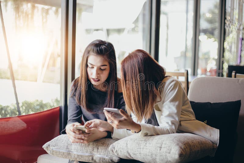 Młoda dziewczyna patrzeje jej przyjaciela ` s uczucia i telefonu ekscytować obraz stock Młoda dziewczyna patrzeje jej przyjaciela ` s uczucia i telefonu ekscytować obraz stock