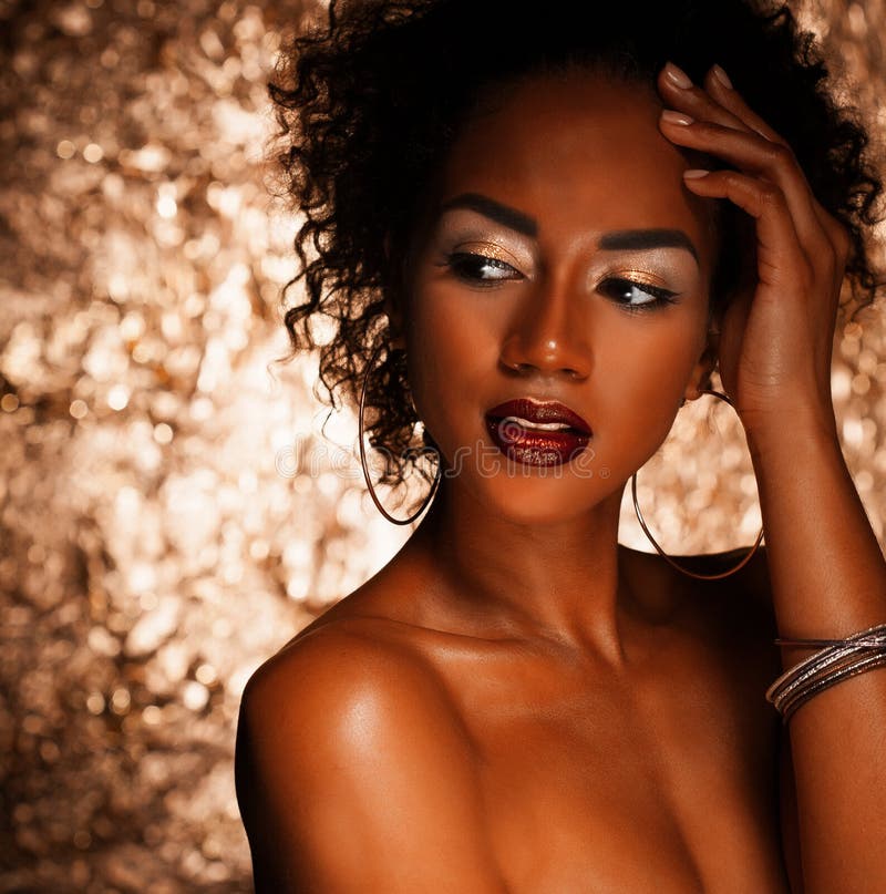Młoda elegancka amerykanin afrykańskiego pochodzenia kobieta z afro włosy Splendoru makeup złoty tło zdjęcia stock Młoda elegancka amerykanin afrykańskiego pochodzenia kobieta z afro włosy Splendoru makeup złoty tło zdjęcia stock