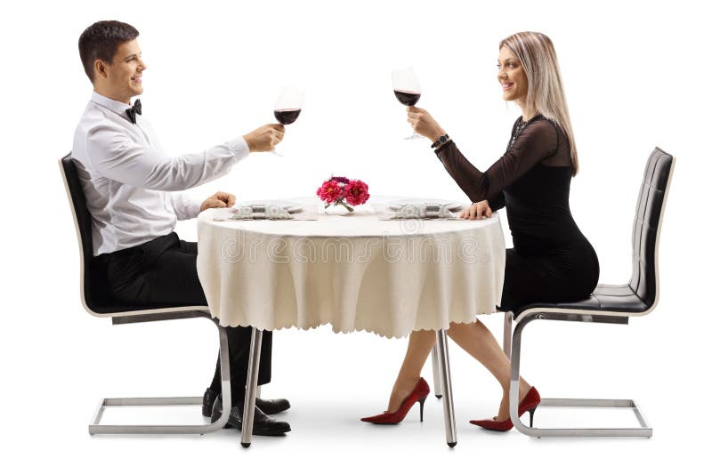 Młoda elegancka para wznosi toast z winem przy stołem zdjęcia stock Młoda elegancka para wznosi toast z winem przy stołem zdjęcia stock