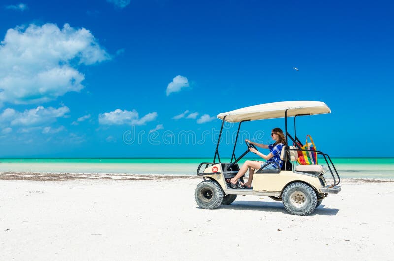 Młoda kobieta jedzie golfową furę przy tropikalną plażą fotografia stock Młoda kobieta jedzie golfową furę przy tropikalną plażą fotografia stock
