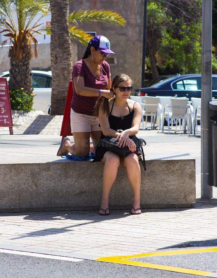 Młoda kobieta jej włosy splatającego i plosącego lokalnym ulicznym handlowem w Playa Las Ameryki w wyspie kanaryjska Teneriffe fotografia royalty free Młoda kobieta jej włosy splatającego i plosącego lokalnym ulicznym handlowem w Playa Las Ameryki w wyspie kanaryjska Teneriffe fotografia royalty free