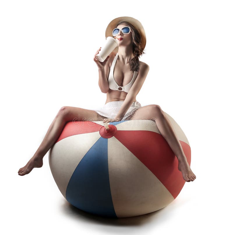 Young beautiful woman sitting on a huge baloon drinking. Young beautiful woman sitting on a huge baloon drinking