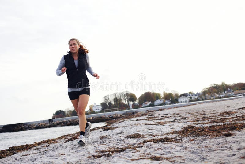 Młoda kobieta jogging wzdłuż plaży zdjęcia stock Młoda kobieta jogging wzdłuż plaży zdjęcia stock