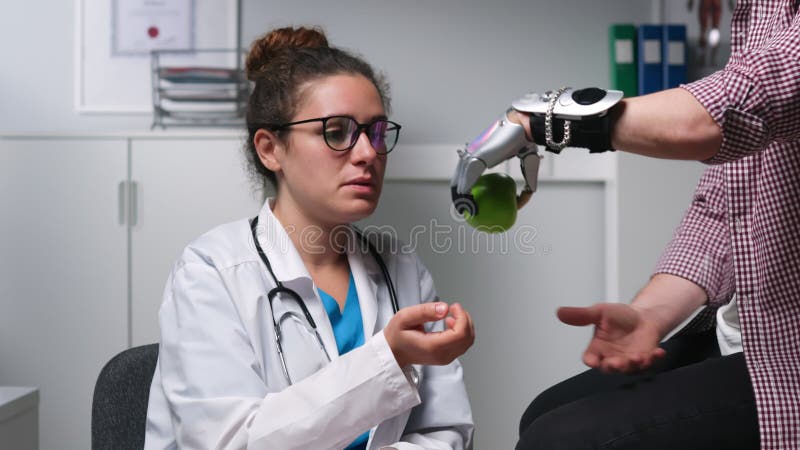 Młoda kobieta lekarz pomaga pacjentowi męskiemu nauczyć się jak stosować bioniczną protezę dłoni