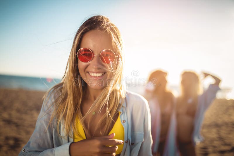Młoda kobieta na plaży z przyjaciółmi w tle Grupa znajomych, którzy cieszą się świętami plażowymi zdjęcie royalty free Młoda kobieta na plaży z przyjaciółmi w tle Grupa znajomych, którzy cieszą się świętami plażowymi zdjęcie royalty free