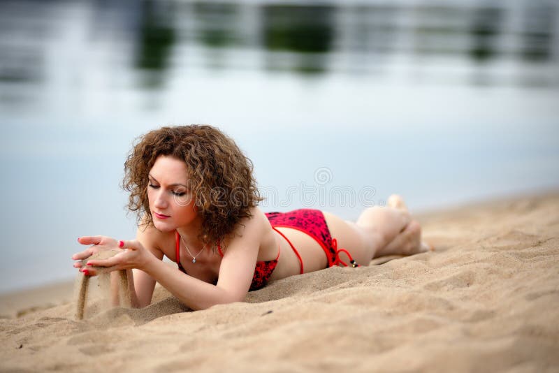Młoda kobieta z fryzowanie włosy kłama na plaży i sztukach z piaskiem