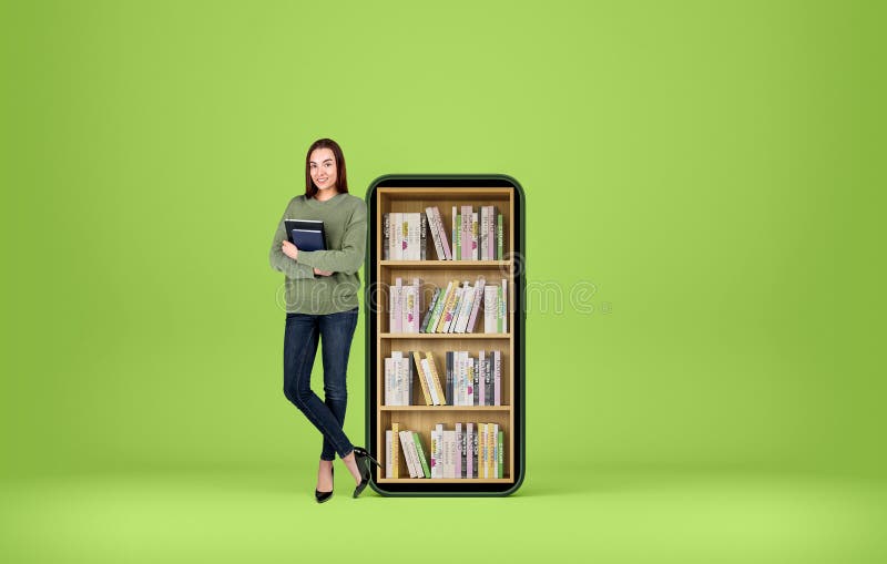 Young smiling woman standing with notebook in hands, full length on green background. Smartphone with books on shelf. Concept of e-learning. Copy space. Young smiling woman standing with notebook in hands, full length on green background. Smartphone with books on shelf. Concept of e-learning. Copy space