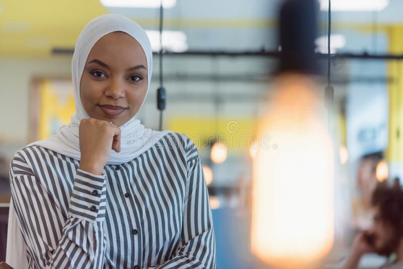 Young muslim African American business women as a leader at work. Teamwork and multiethnic concept. Happy successful business leader posing while her team in background. Young muslim African American business women as a leader at work. Teamwork and multiethnic concept. Happy successful business leader posing while her team in background.