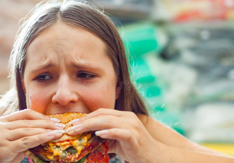 Młoda nastoletnia dziewczyna je hamburger Dziewczyna próbuje jeść fast food fotografia stock Młoda nastoletnia dziewczyna je hamburger Dziewczyna próbuje jeść fast food fotografia stock