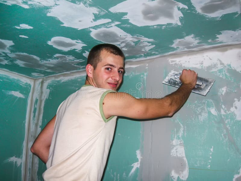 Młoda osoba pracuje indoors na plasterboard gipsowaniu fotografia stock Młoda osoba pracuje indoors na plasterboard gipsowaniu fotografia stock
