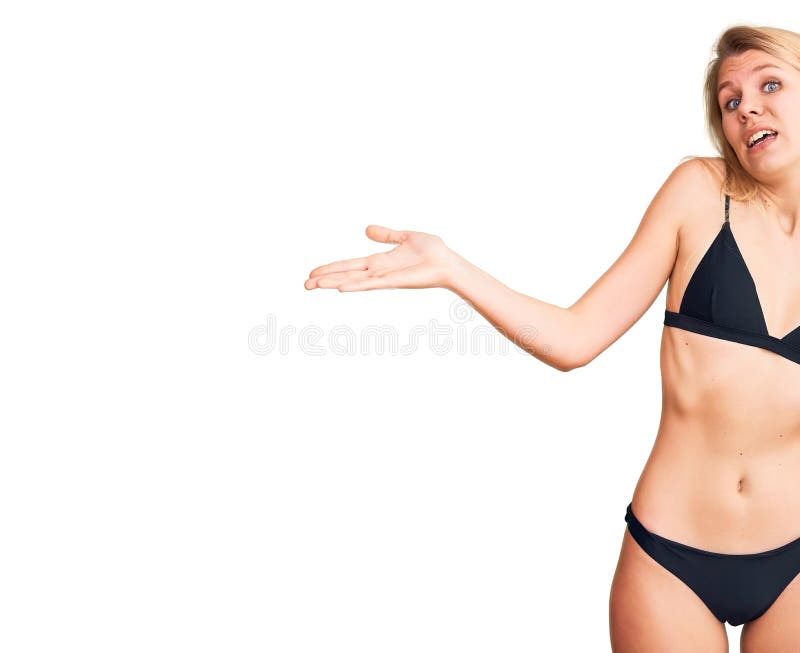 Młoda, piękna blondynka, ubrana w bikini, nieokiełznana i zmieszana ekspresja z podniesionymi rękami i rękami fotografia royalty free