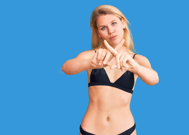 Młoda piękna blondynka w bikini wyrażenie odrzucenia skrzyżowania palców z negatywnym znakiem zdjęcie stock